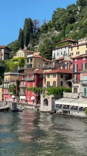 Tourist enjoys gelato amid colorful buildings in Varenna, Italy