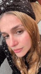 Woman photographed enjoying snowfall in winter clothing