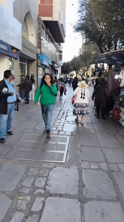 Pedestrians walk along La Paz street in evening hours