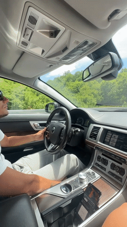 Couple drives through Montenegro hills, woman gestures from passenger seat