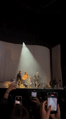 Female singer performs acoustic set with band in London arena