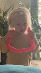 Child plays with pink pop tube toy in Petah Tikva