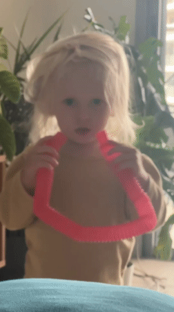 Child plays with pink pop tube toy in Petah Tikva