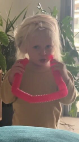Child plays with pink pop tube toy in Petah Tikva