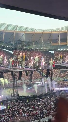 Live stadium concert in London, big stage, packed crowd.