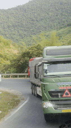 Two trucks navigate mountain road in Vietnam