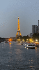 Eiffel Tower glowing at dusk, seen from the Seine