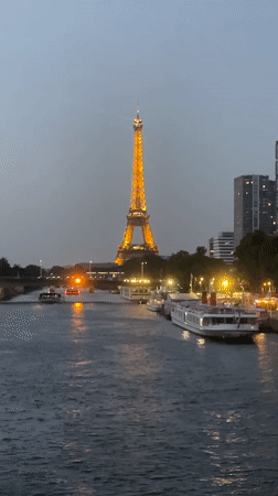 Eiffel Tower glowing at dusk, seen from the Seine