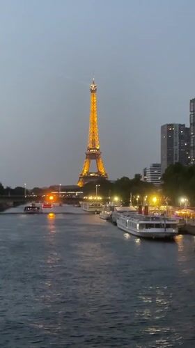 Eiffel Tower glowing at dusk, seen from the Seine