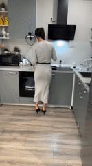 Woman in grey dress cooking in kitchen