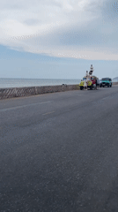 Group poses for photos around yellow vehicle near Vietnamese beach
