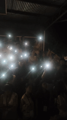 Indoor event attendees use phone flashlights in darkened venue