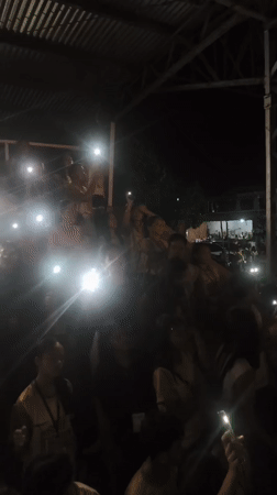 Indoor event attendees use phone flashlights in darkened venue