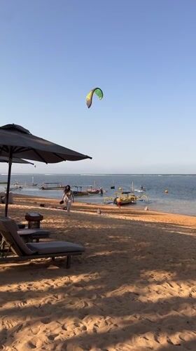 Bali beach morning: kites, outriggers, and calm water