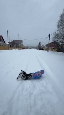 Child plays in deep snow on residential street in Russia