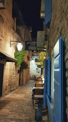 Nighttime cobblestone alley with lanterns and blue shutters documented