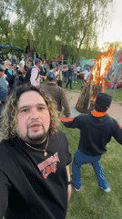 Man films outdoor gathering with crowd, bonfire in Moldova