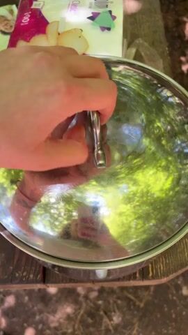 A pair of hands lifts a metal lid off of a metal bowl containing thin, flat bread. The hands then move some of the bread to reveal cooked meat underneath.