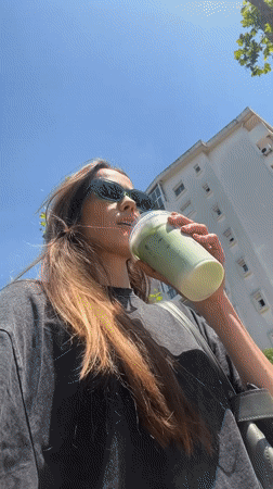 Woman enjoys iced matcha latte from Olive Coffee in Bar