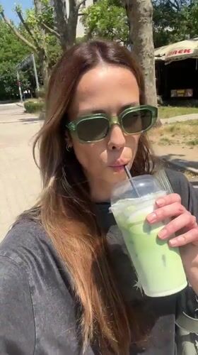 Woman enjoys iced matcha latte from Olive Coffee in Bar