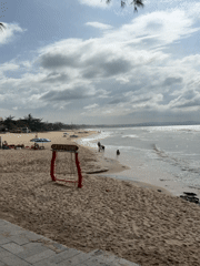 Surfers and beachgoers along the Phan Thiết coast on an overcast morning