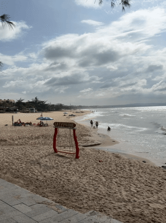Surfers and beachgoers along the Phan Thiết coast on an overcast morning