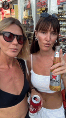 Two women walk sidewalk in North Kuta, one holds beer