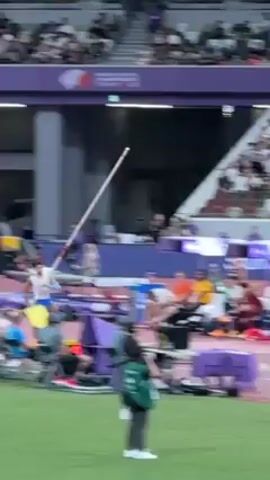 Here's a brief description of the video:

The video shows a pole vaulter performing at a stadium. The athlete, wearing a blue and white uniform, runs down the runway, plants the pole, and vaults over the bar. The crowd cheers as he clears the bar. The stadium is packed with spectators.