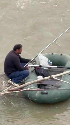 Man fishing from green boat on Georgian river