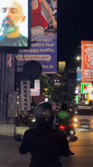 Motorcyclist rides through North Kuta street traffic amid illuminated signs
