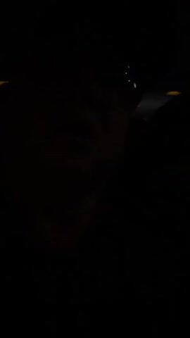 The video is extremely dark, making it difficult to discern details. However, it appears to show a few people inside what could be a vehicle or a dimly lit indoor space. The camera is moving, suggesting it's handheld or inside a vehicle in motion. There are some faint lights visible, possibly from the outside or from within the space, but they are not bright enough to illuminate the surroundings clearly. The audio is also muffled and unclear. It's impossible to identify individuals or specific objects due to the poor lighting conditions.