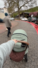 Parent pushes stroller along wet cobblestone street in Bad Kreuznach