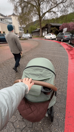 Parent pushes stroller along wet cobblestone street in Bad Kreuznach