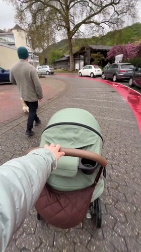 Parent pushes stroller along wet cobblestone street in Bad Kreuznach