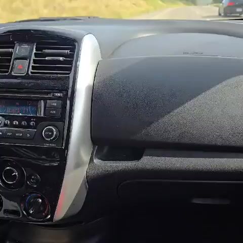 The video shows the dashboard of a car while driving. The focus shifts to the car's radio, which is playing a CD, specifically track 11, at 12:30. The radio display is dusty.  The car is moving, as seen by the changing scenery outside the windshield.