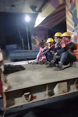 Construction workers ride truck flatbed under Dhaka highway overpass