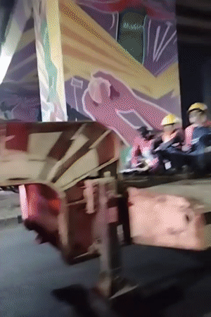 Construction workers ride truck flatbed under Dhaka highway overpass