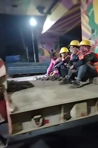Construction workers ride truck flatbed under Dhaka highway overpass