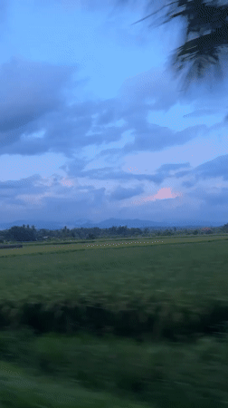 Vehicle travels through rural Mendoyo landscape at dusk