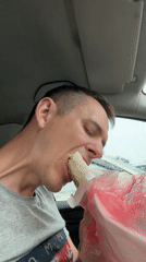 Driver eats shawarma in car during rainy afternoon
