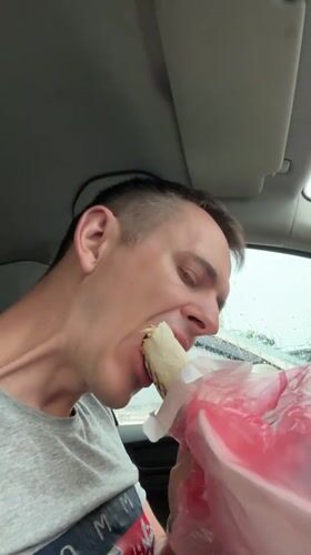 Driver eats shawarma in car during rainy afternoon