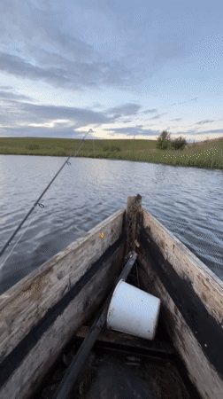 Fishing from a wooden rowboat at dusk, rural Belarus