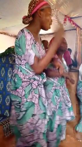 Women dance in matching dresses at indoor celebration in Makungu