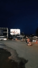 Motorcycle with two riders crosses intersection in Lhokseumawe at night