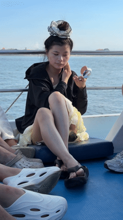 Woman applies makeup on boat bench in Sukawati