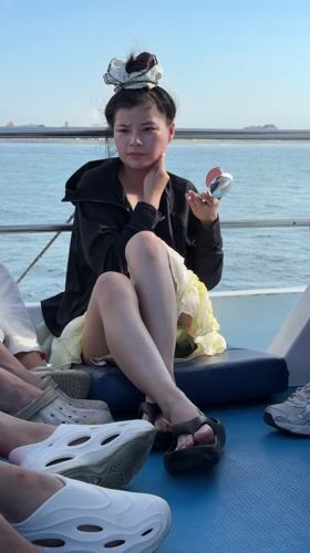 Woman applies makeup on boat bench in Sukawati