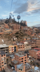 Cable car passengers document La Paz cityscape at sunset