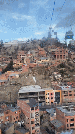 Cable car passengers document La Paz cityscape at sunset