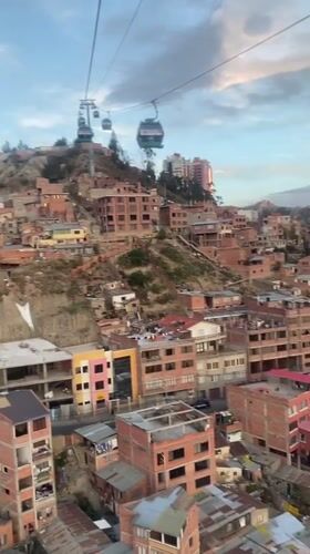 Cable car passengers document La Paz cityscape at sunset