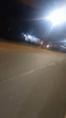 Nighttime traffic recorded on illuminated Jos road with parked trucks